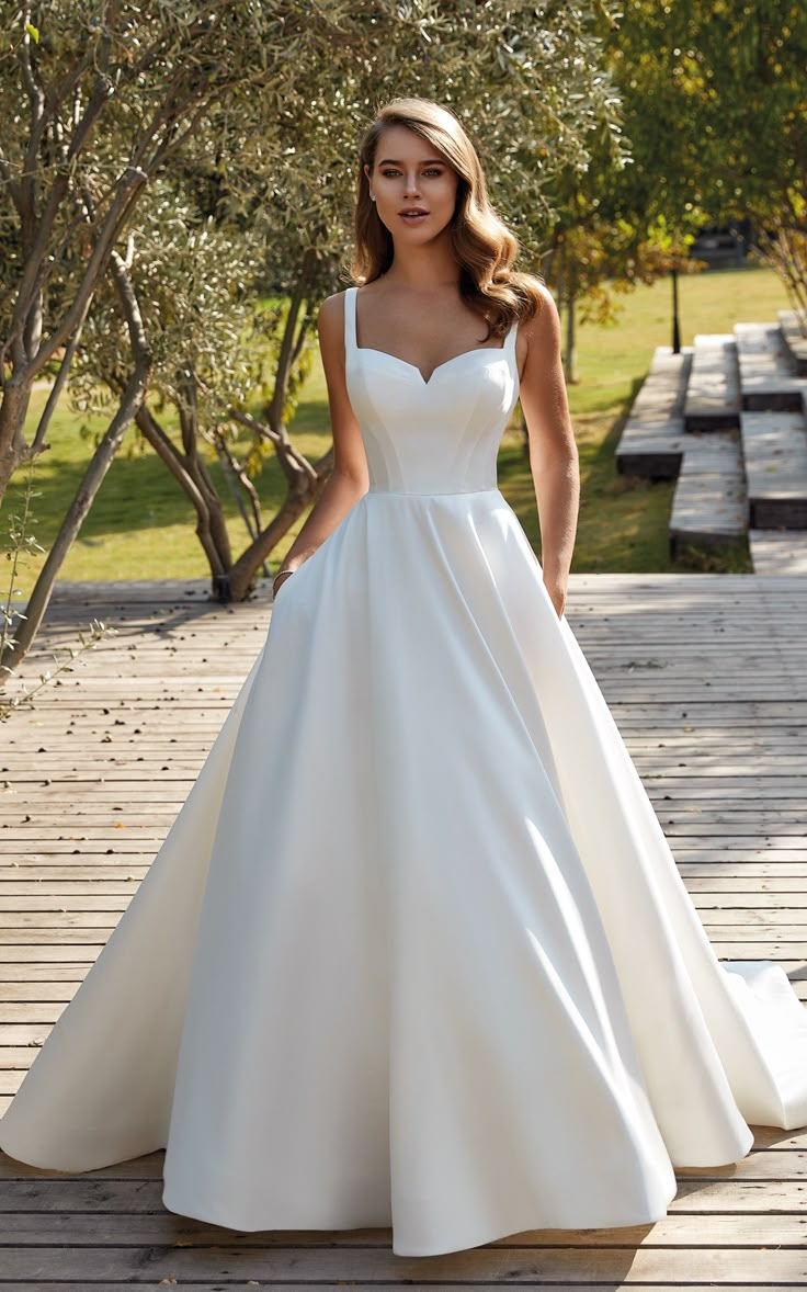 a woman in a white wedding dress standing on a wooden deck