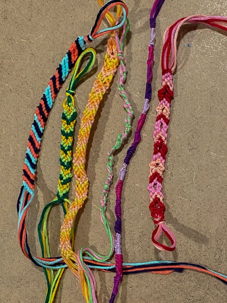 several colorful bracelets laid out on the ground next to each other, all tied together