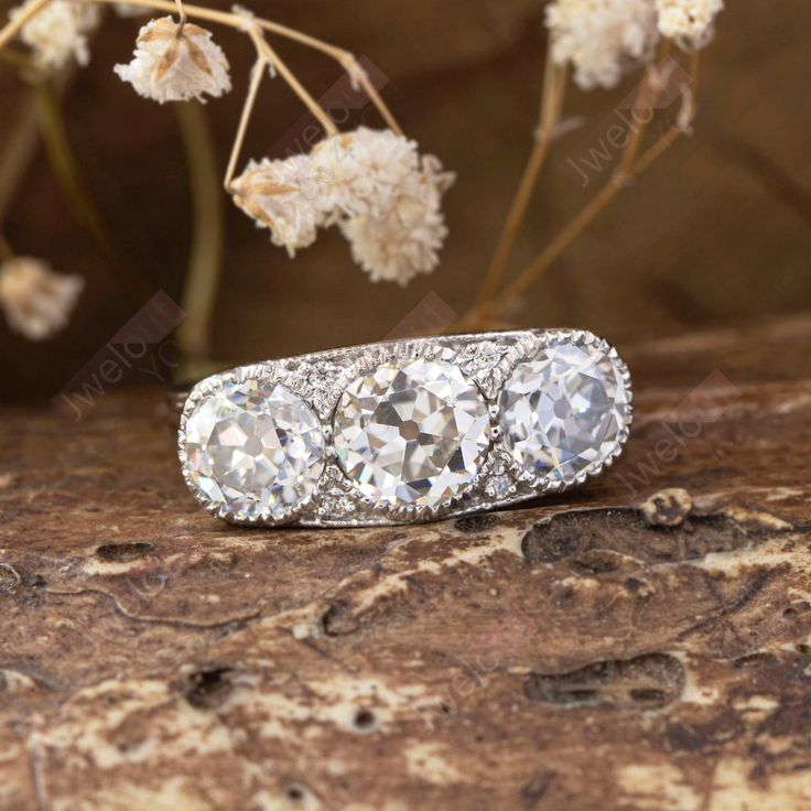 three stone diamond ring sitting on top of a rock