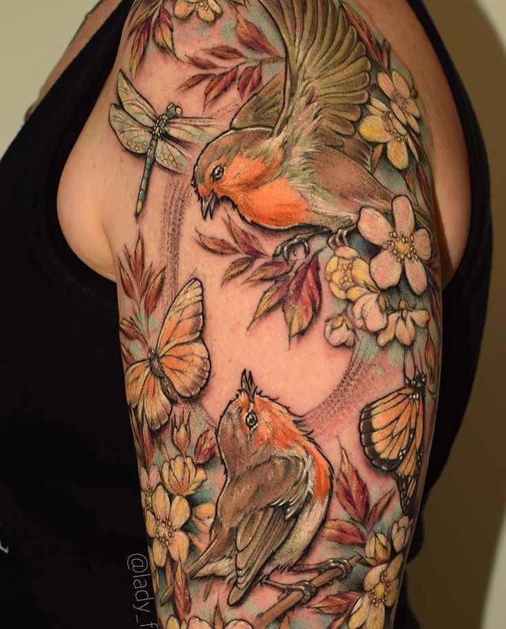 a woman's arm with flowers, butterflies and birds on the back of her shoulder