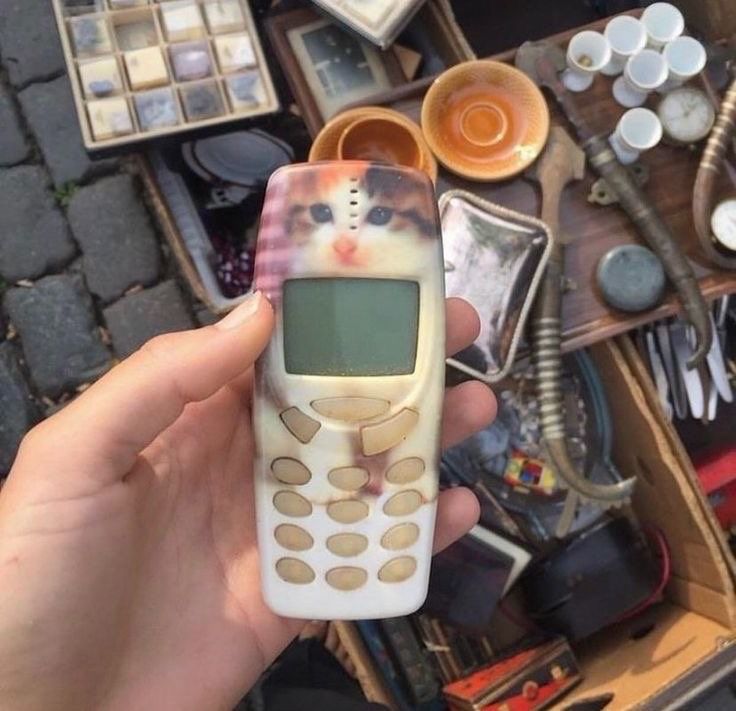 a person holding a cell phone in their hand with other items on the table behind them