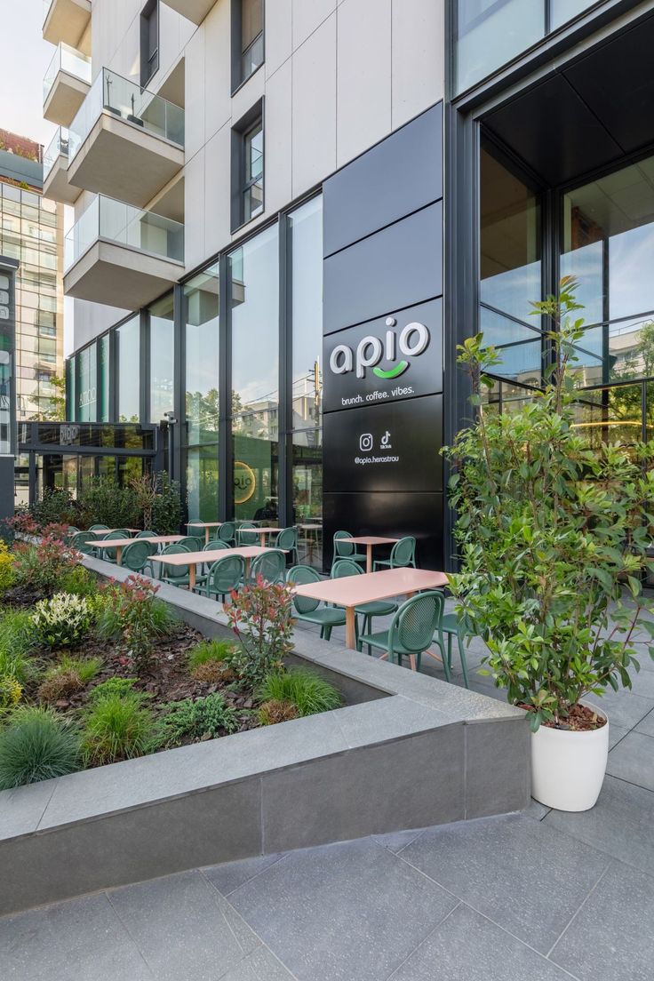 the outside of an office building with tables and chairs in front of it, surrounded by plants