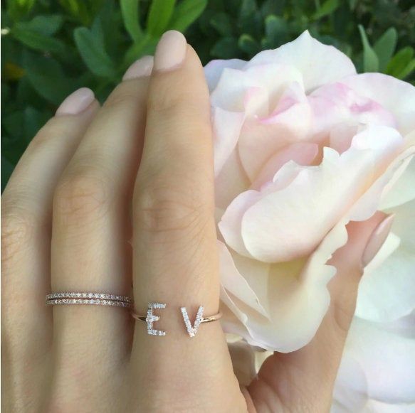 a woman's hand with a diamond ring on it and a flower in the background