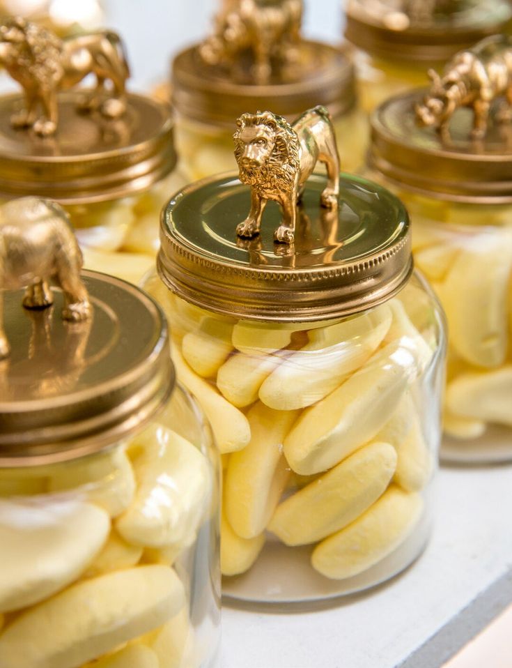 several glass jars filled with yellow candy and gold figurines on top of each other