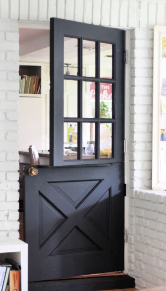 a black door with a glass pane on the top and side panels is in front of a white brick wall