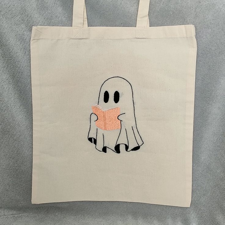 "Reading Ghost" Stitches are secured from inside of bag :) Measurements: 38 cm x 41 cm (14.96 inch x 16.14 inch) Handles: 70 cm (27 inch) Contact me on Instagram: @szczesliwasztuka Thank you for supporting my small handmade business! Diy Halloween Canvas Bags, Tot Bag Broderie, Ghost Cat Embroidery, Creative Tote Bag, Cute Cat Design Tote Bag, Painted Canvas Bags, Everyday Halloween Tote Bag, Handpainted Tote Bags, Ghost Tote Bag