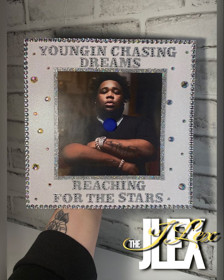 a person's hand holding up a photo frame with the words youngin chasing dreams reaching for the stars on it