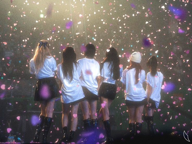 the girls are standing in front of confetti on the stage with their backs to the camera