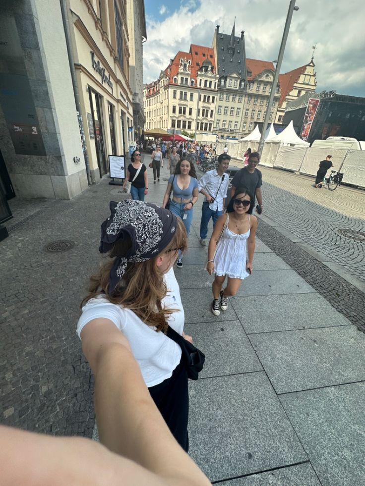 a group of people walking down a street next to tall buildings