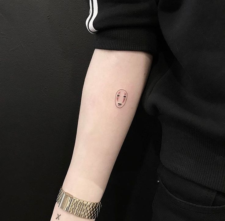 a person with a small face tattoo on their arm