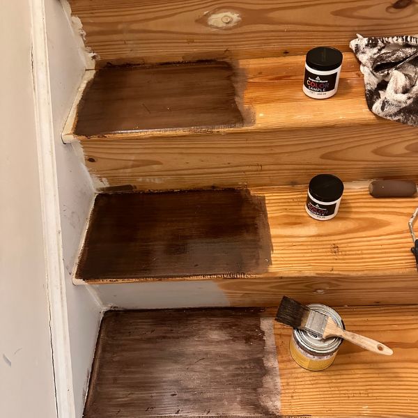 the stairs are being painted brown with paint and brushes on them, along with other items