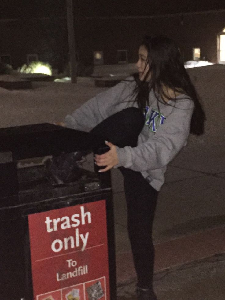 a woman standing next to a trash can