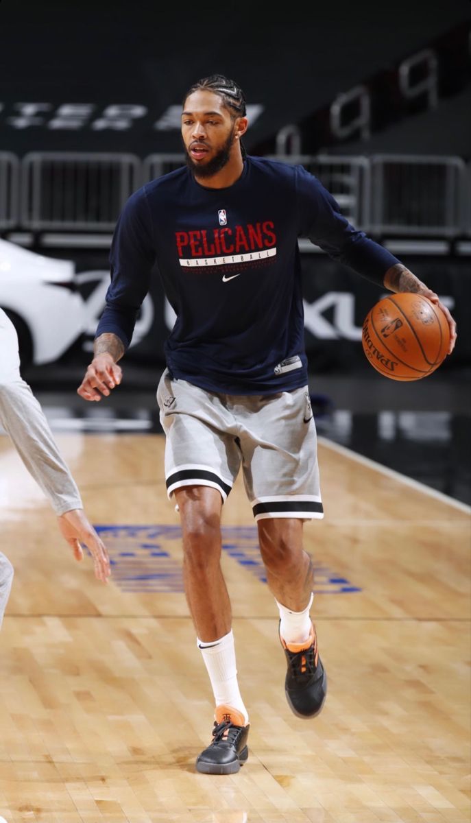 a man dribbling a basketball on top of a court with another man in the background