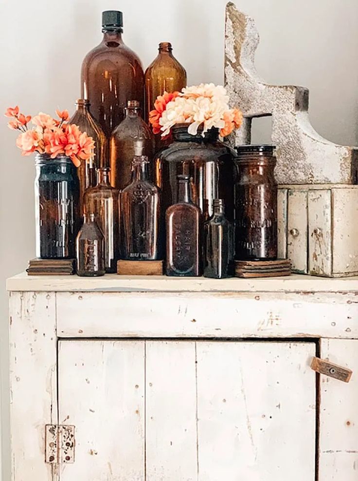 an old dresser with many bottles and flowers on it