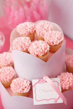 pink cupcakes are arranged on a cake stand with a card in the middle