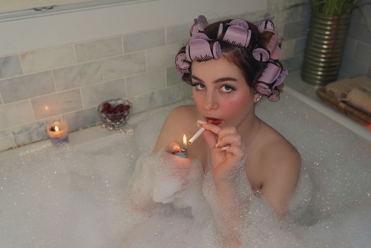 a woman sitting in a bathtub holding a lit candle