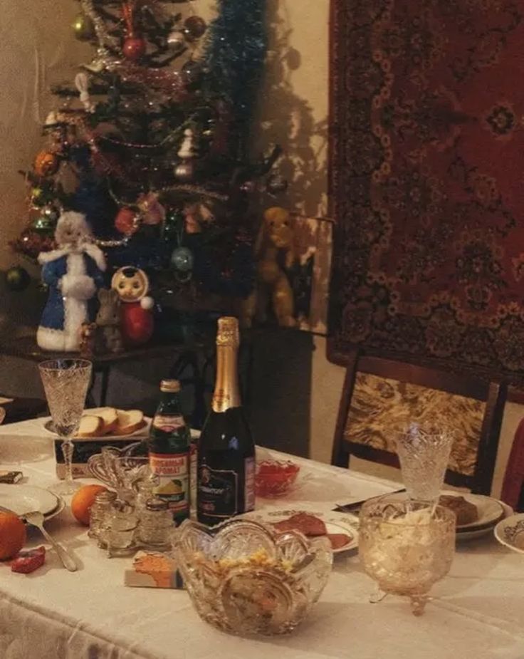 a dining room table set for christmas dinner with wine, bread and fruit on it