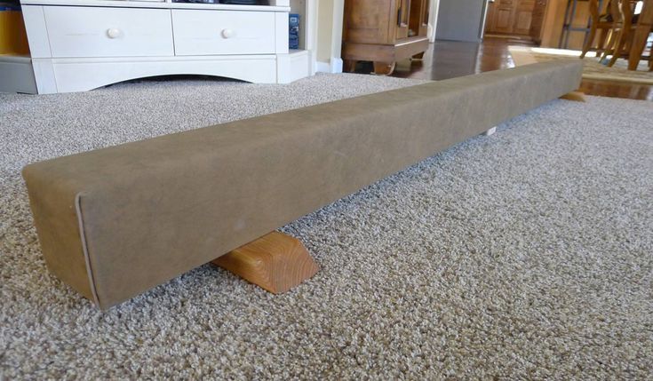 a wooden bench sitting on top of a carpeted floor next to a white dresser