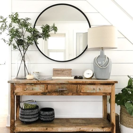 a wooden table topped with a mirror next to a vase filled with flowers and plants