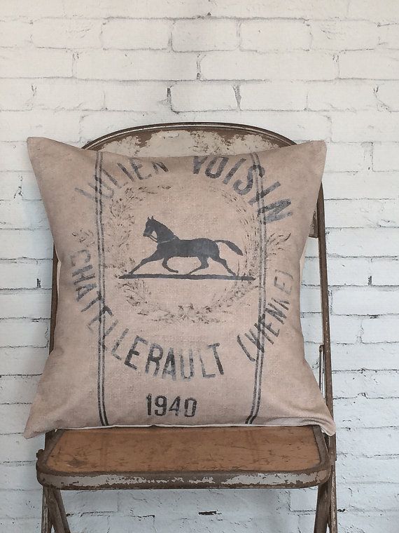 an old chair with a pillow that has a horse on it, against a white brick wall