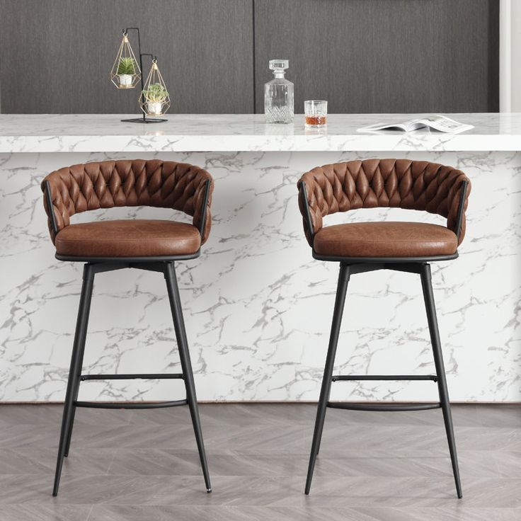 two brown leather barstools sitting in front of a marble counter