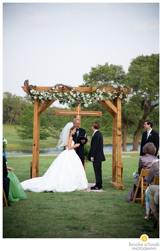 the bride and groom are getting married under an arbor with flowers on it at their wedding ceremony