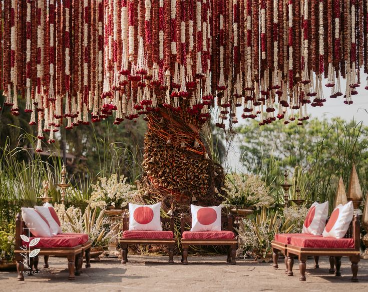 red and white pillows are hanging from the ceiling in front of some chairs with cushions on them