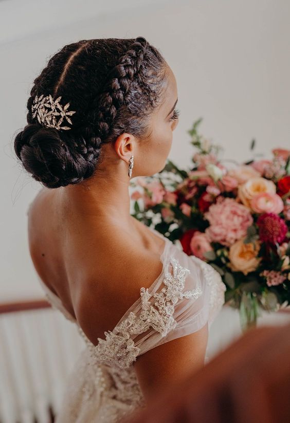 a woman in a wedding dress standing next to a flower bouquet and looking down at her hair