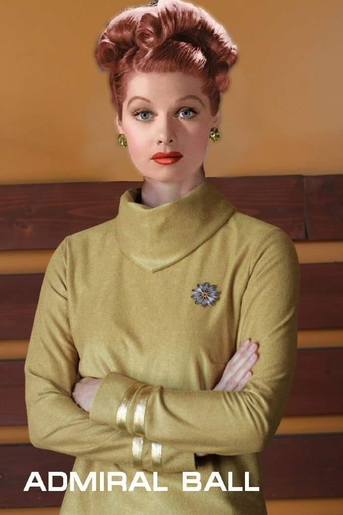 a woman with her arms crossed standing in front of a wooden bench wearing a gold dress