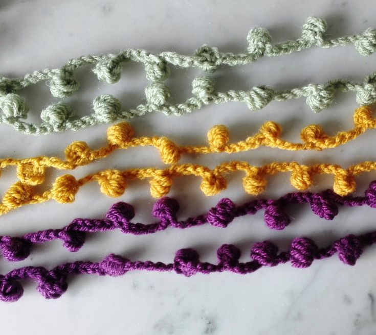 four crocheted pieces of different colors on a marble counter top, one is yellow and the other is purple