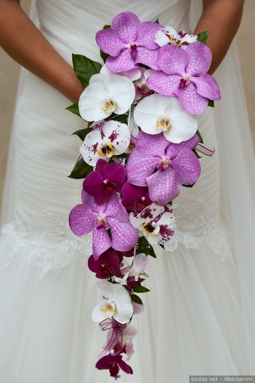 a bride holding a bouquet of purple and white orchids