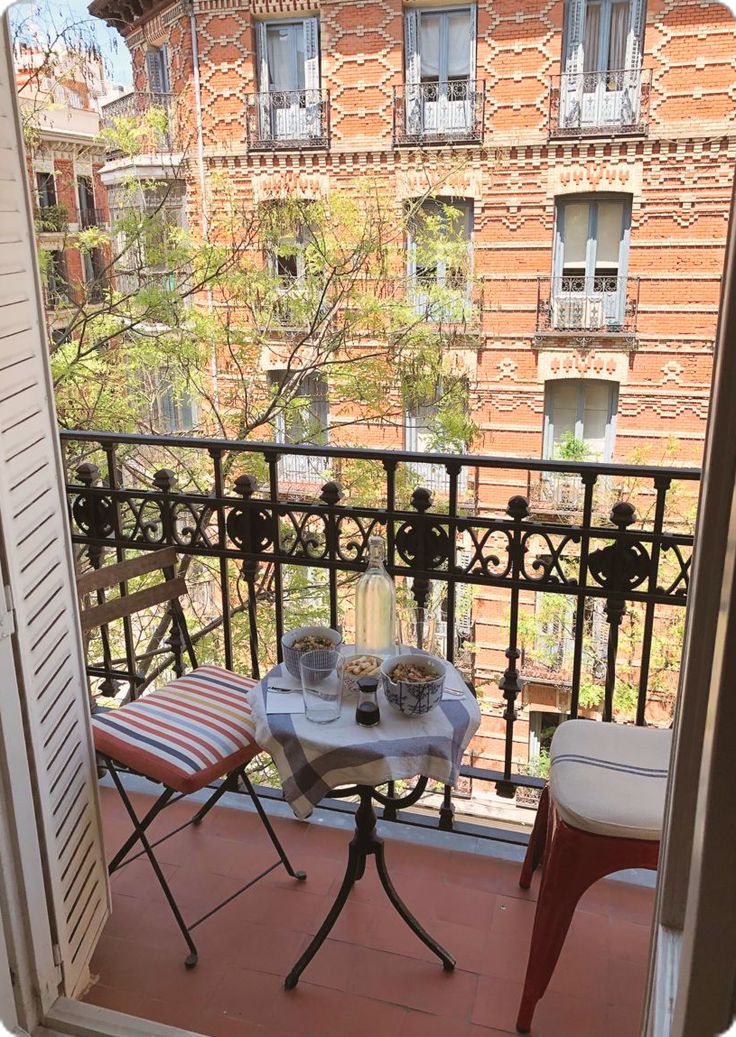 an open balcony door with a table and chairs on it