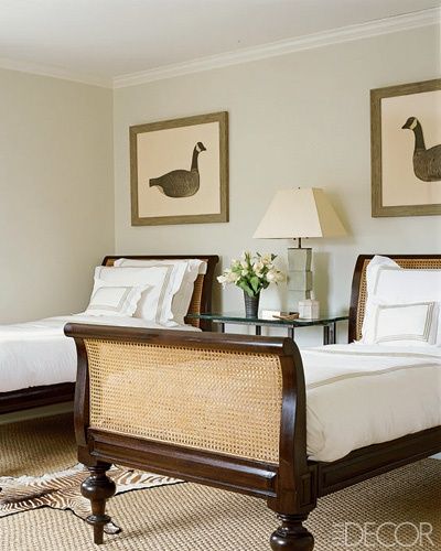 two beds in a bedroom with white linens and brown wood frames, one has a duck painting on the wall