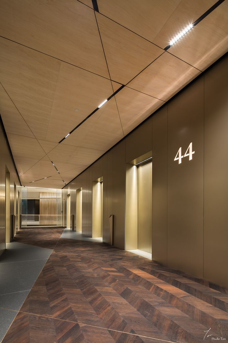 an empty hallway with wooden floors and lights on the ceiling is lit by recessed lighting