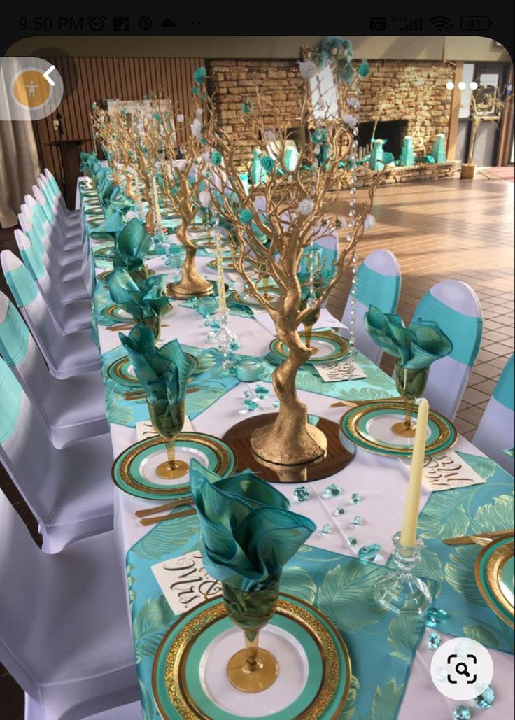 the table is set with teal and gold place settings for an elegant dinner party