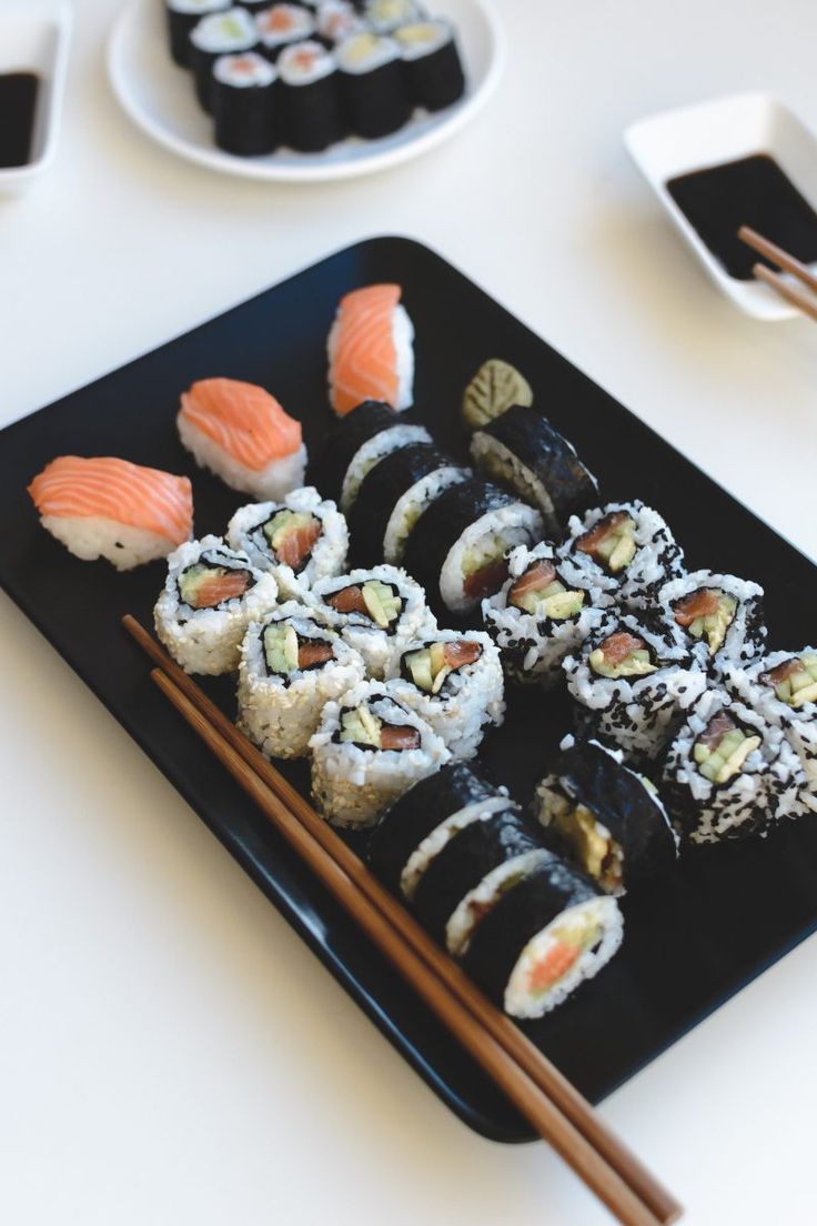 sushi on a black plate with chopsticks next to it