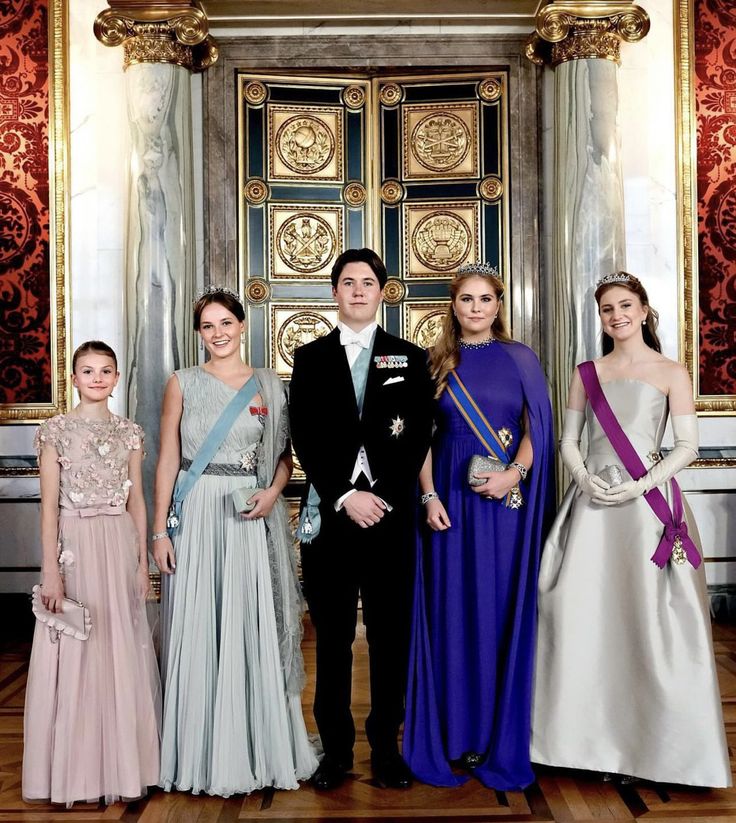 a group of people standing next to each other in front of a door wearing gowns