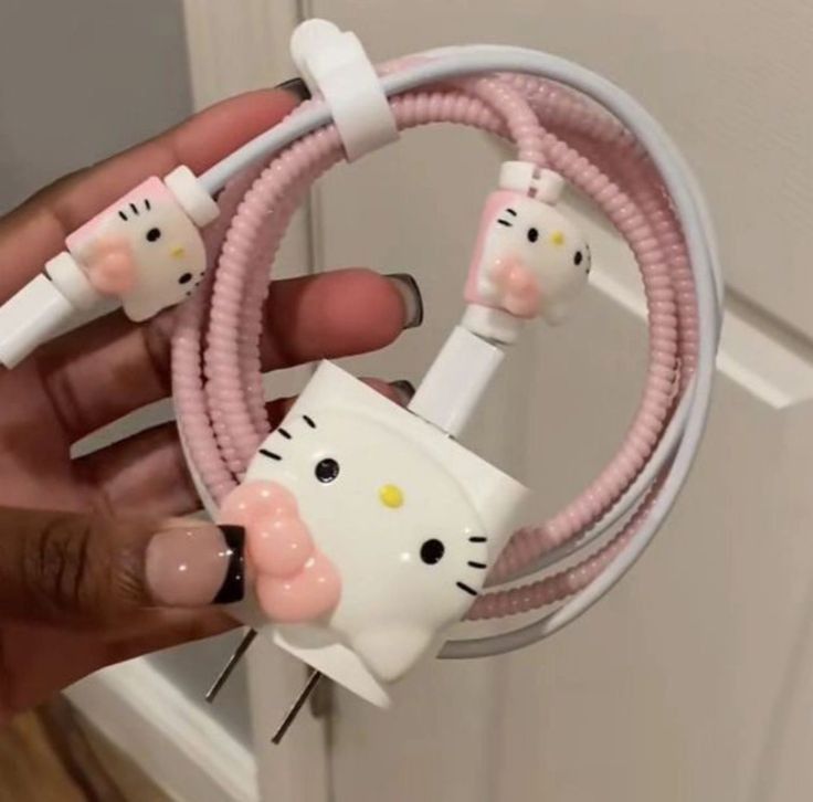 a person holding a hello kitty cable with two cats plugged into the cord and attached to it