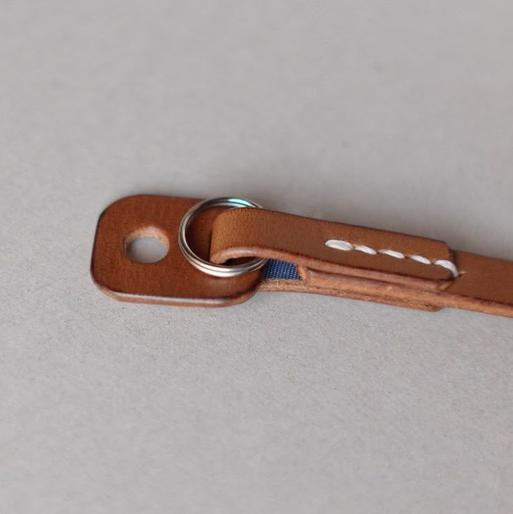 a leather keychain with a metal ring on it's end, sitting on a white surface