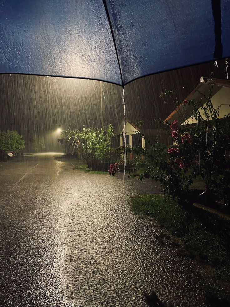 an open umbrella sitting on the side of a road in the rain at night time