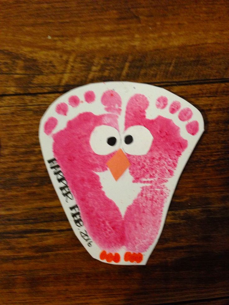 a pink handprinted bird on top of a wooden table