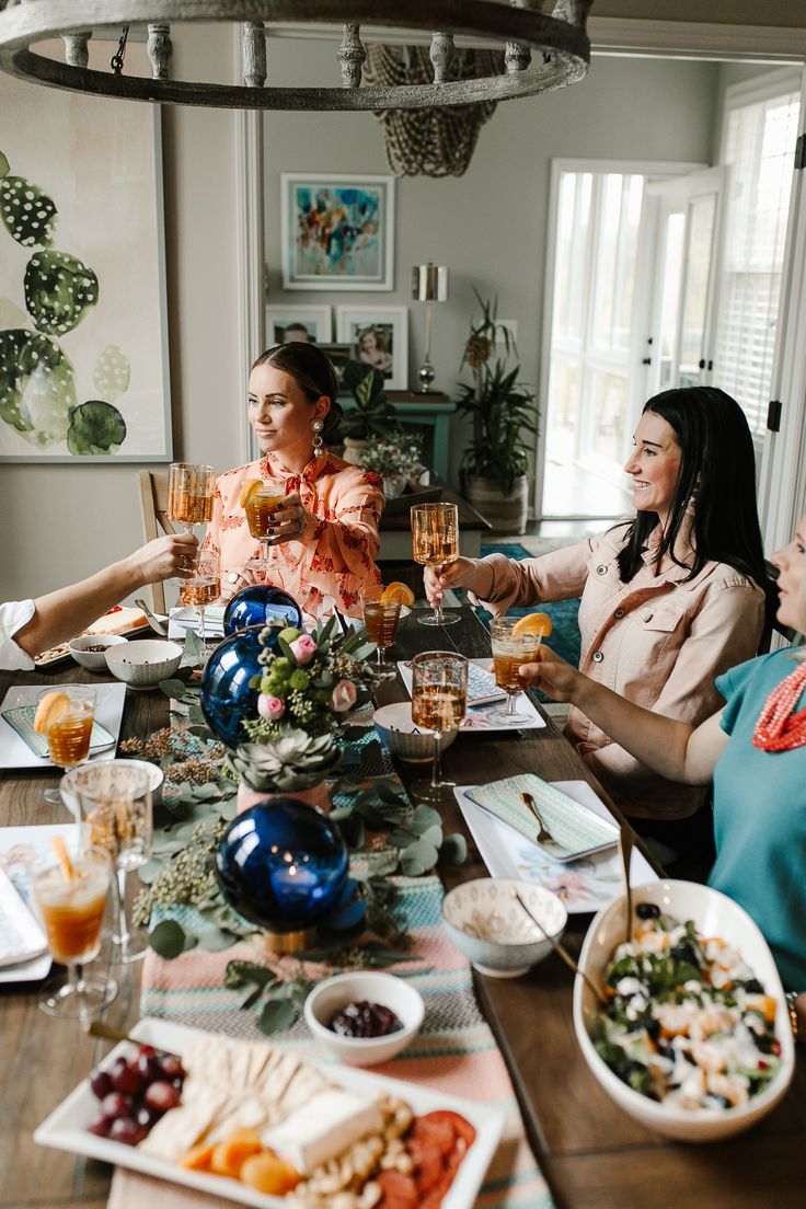 three women sitting at a table with food and drinks