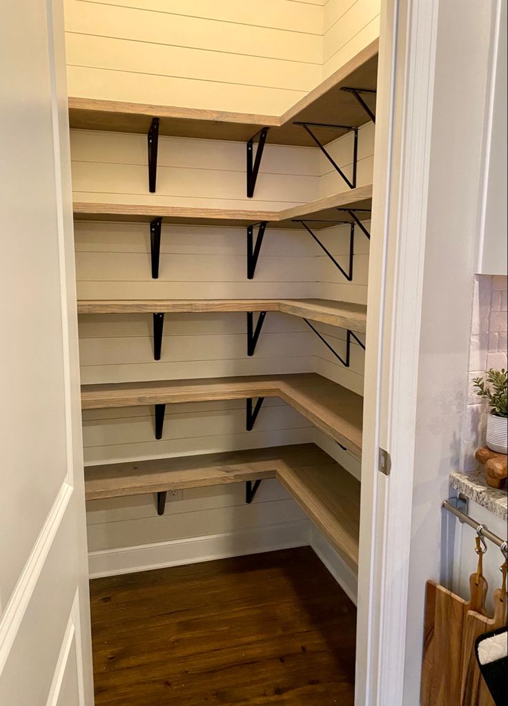 an empty walk in closet with wooden shelves and black brackets on the wall above it