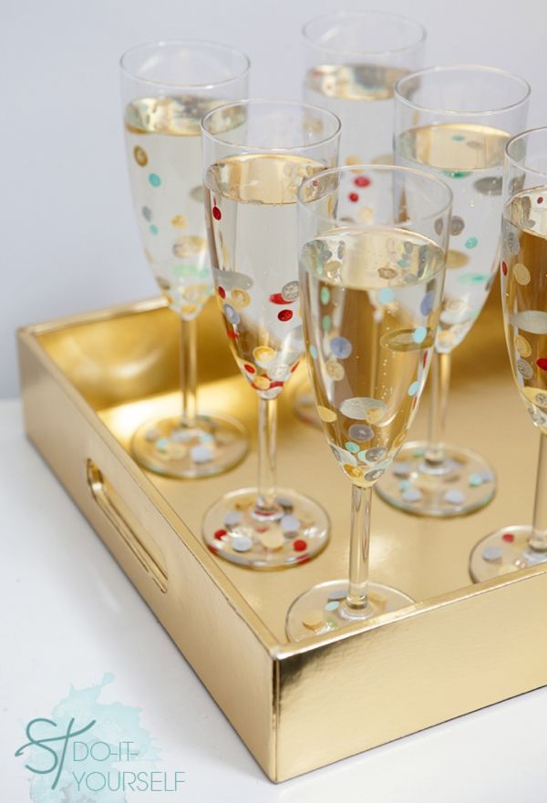 several champagne glasses are sitting on a gold tray with confetti in them,