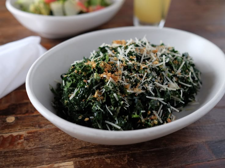 a white bowl filled with spinach and cheese next to a glass of orange juice