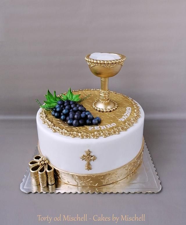 a cake decorated with grapes and a chalicette sits on a platter next to a candle