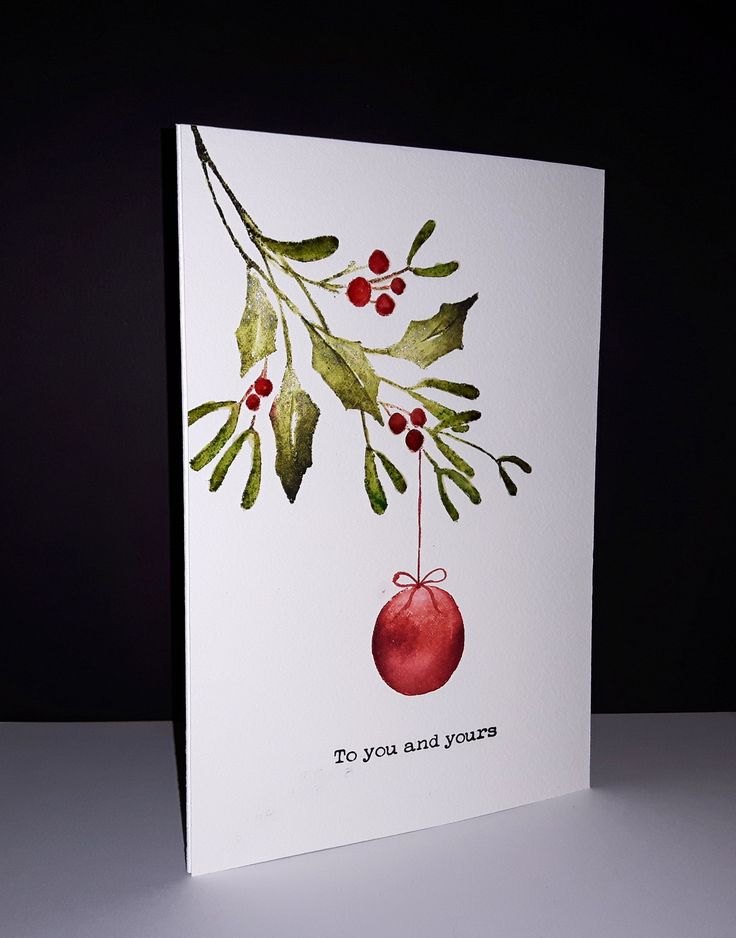 a christmas card with an ornament hanging from it's side on a table