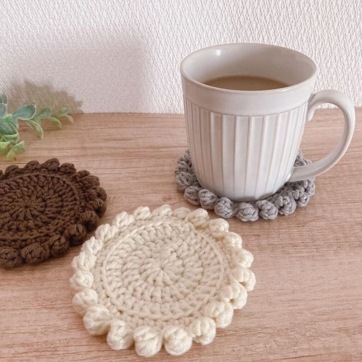 two crocheted coasters next to a cup of coffee