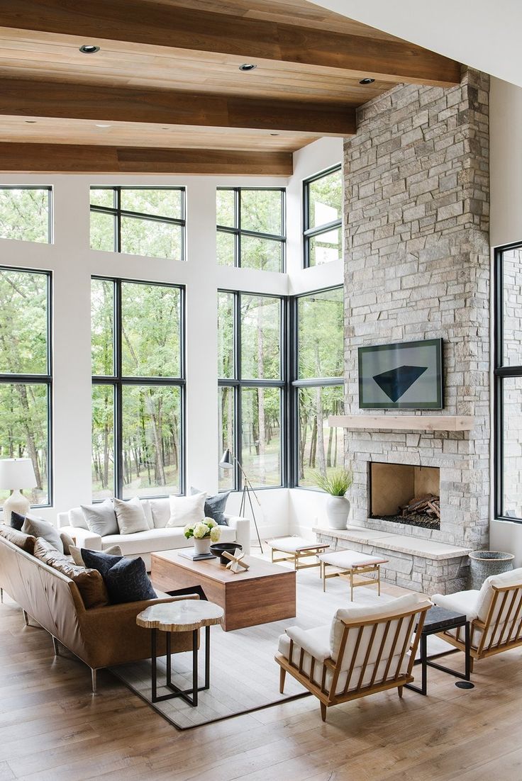 a living room filled with lots of furniture next to large windows on top of a hard wood floor