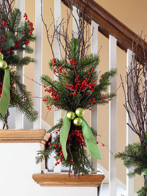 christmas decorations on the banisters and stairs are decorated with greenery, red berries, pine cones and green bow